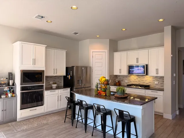 a kitchen with stainless steel appliances a stove a refrigerator and a dining table with wooden floor