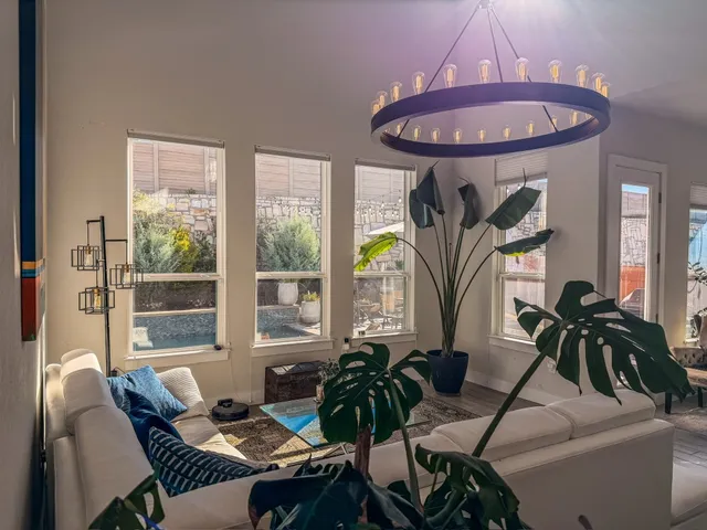 a living room with furniture a chandelier and a floor to ceiling window