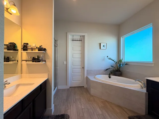 a bathroom with a tub a sink and a large mirror