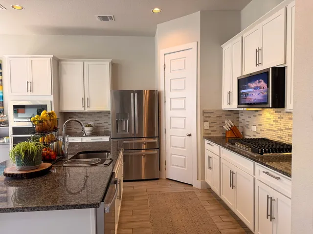 a kitchen with stainless steel appliances granite countertop a refrigerator sink and stove
