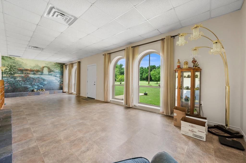 2101 Ridge View Drive Cleburne, TX 76033 - Photo 9 of 31 Spacious room featuring three large arched windows, tile flooring, a detailed wall mural, and a drop-tile ceiling