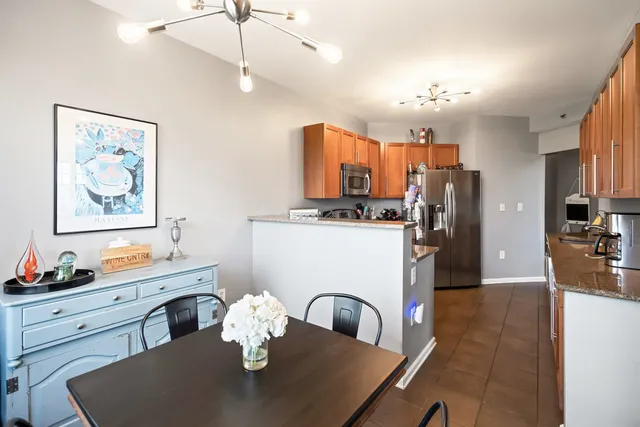 a kitchen with a refrigerator a stove a sink a dining table and chairs with wooden floor