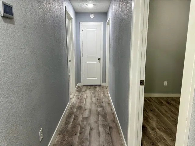 a view of a hallway with wooden floor and a bathroom