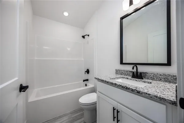a bathroom with a granite countertop sink a toilet and a mirror