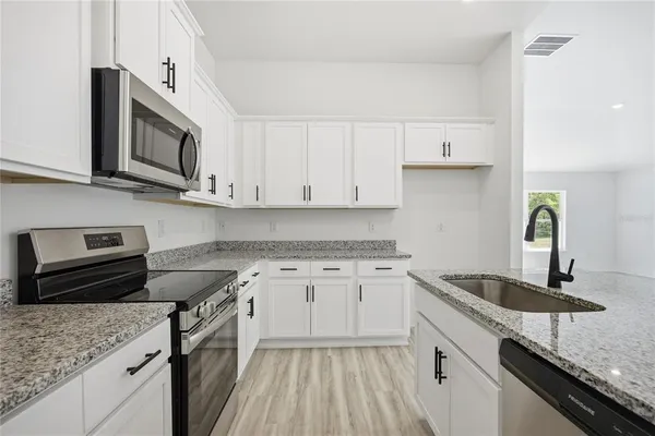 a kitchen with stainless steel appliances granite countertop a sink stove and microwave