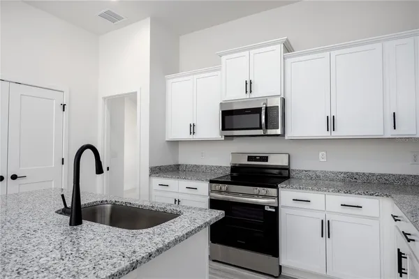 a kitchen with stainless steel appliances granite countertop a sink a stove and a refrigerator