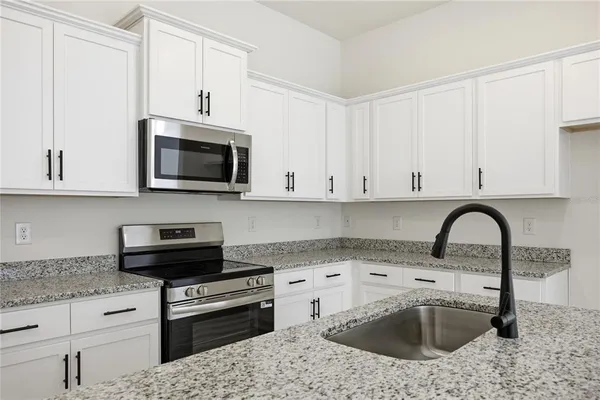 a kitchen with stainless steel appliances granite countertop a sink a stove a microwave and cabinets