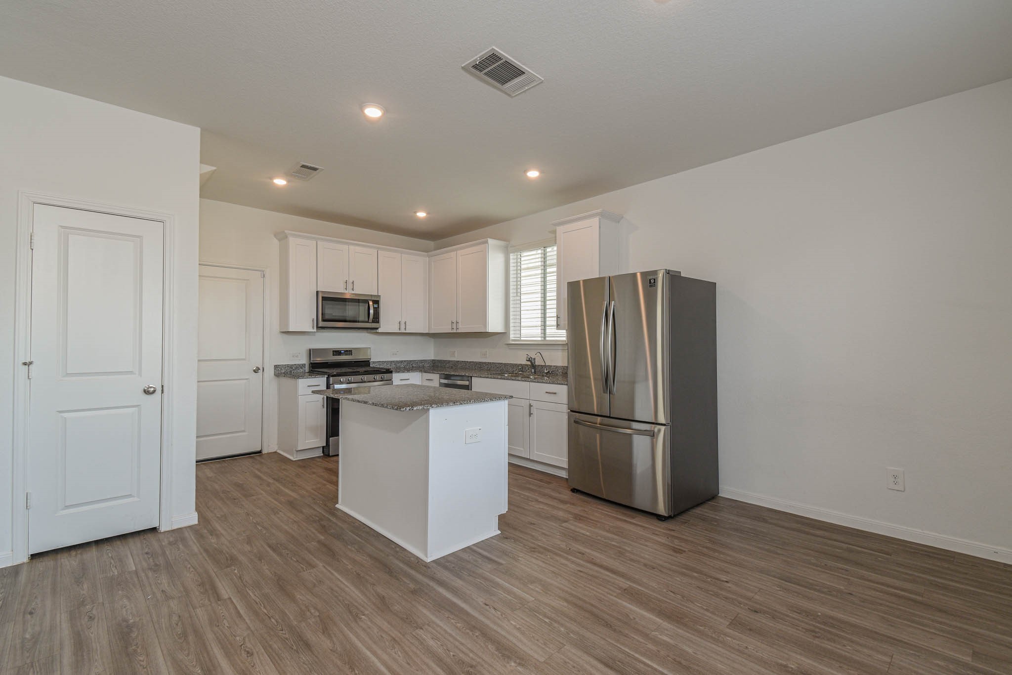 5727 Finely Run Street Spring, TX 77373 - Photo 3 of 26 a kitchen with stainless steel appliances granite countertop a refrigerator stove and wooden floor