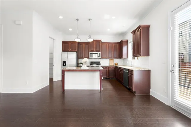 a kitchen with stainless steel appliances kitchen island granite countertop a stove a sink a refrigerator and a microwave