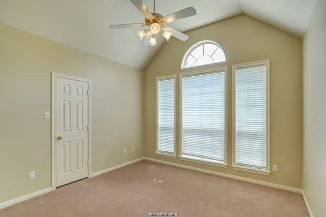 an empty room with windows and ceiling fan