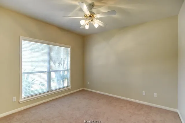 an empty room with a chandelier fan and windows