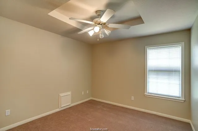 an empty room with a ceiling fan and window