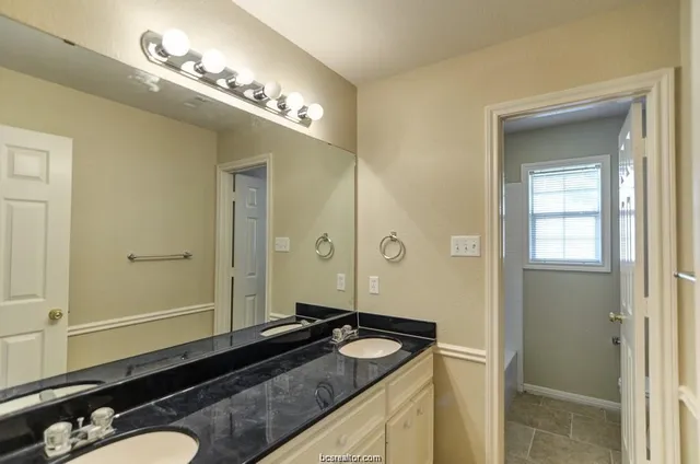 a bathroom with a granite countertop sink and a mirror