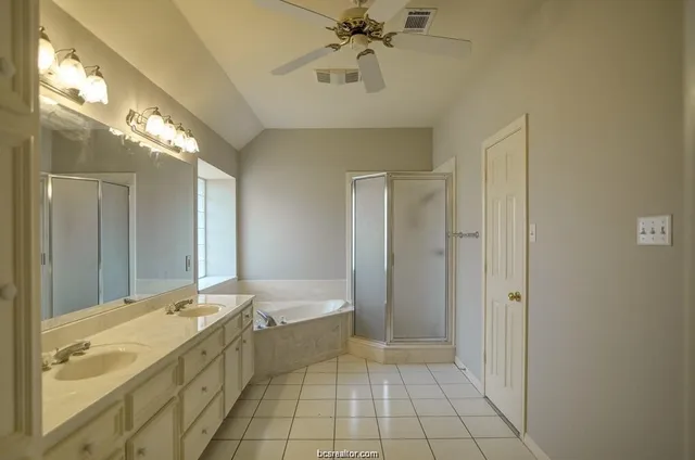 a spacious bathroom with a granite countertop sink a mirror and a bathtub