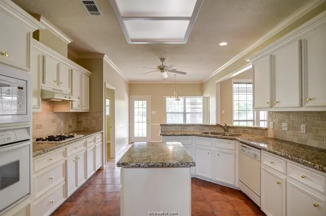 a kitchen with stainless steel appliances granite countertop a sink stove and cabinets