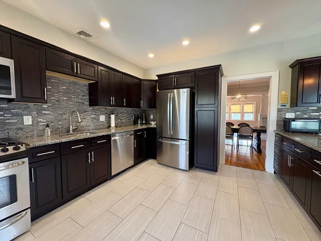 a kitchen with stainless steel appliances granite countertop a refrigerator a sink a stove a microwave and a counter top space