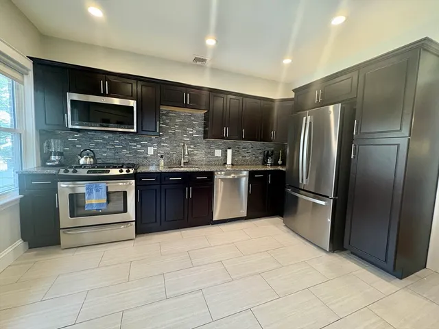 a kitchen with stainless steel appliances granite countertop a stove top oven microwave and refrigerator