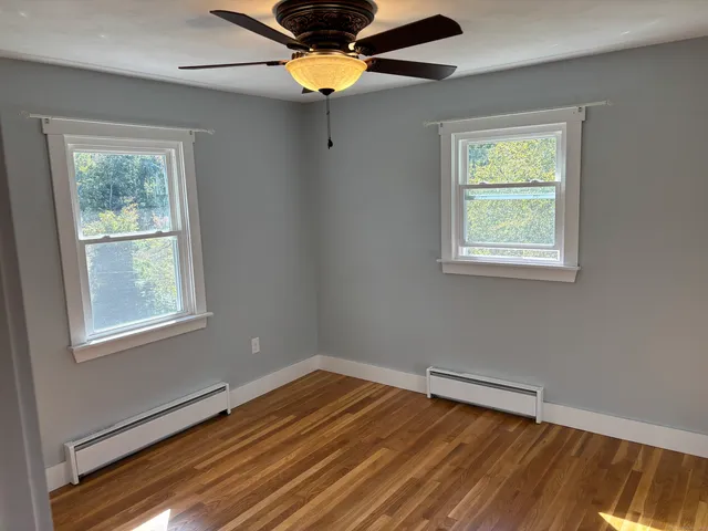 a view of an empty room with wooden floor and a window