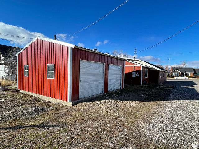 255 West Main Street Mount Pleasant, UT 84647 - Photo 31 of 35 Red metal-sided outbuilding featuring a pitched roofline and two white roll-up garage doors