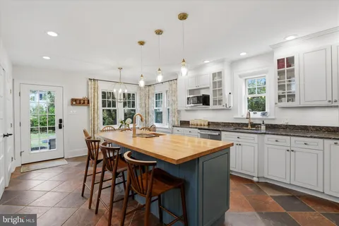 a kitchen with stainless steel appliances granite countertop a stove a sink a oven a dining table and chairs