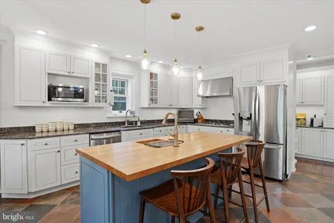 a kitchen with stainless steel appliances granite countertop a table chairs stove microwave and cabinets