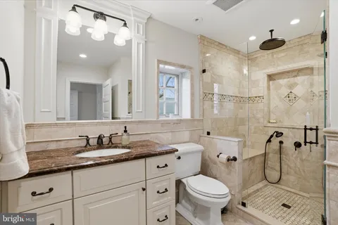 a bathroom with a granite countertop toilet sink and mirror