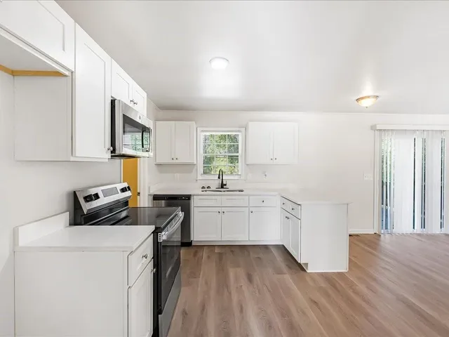 a kitchen that has a lot of cabinets in it and wooden floors