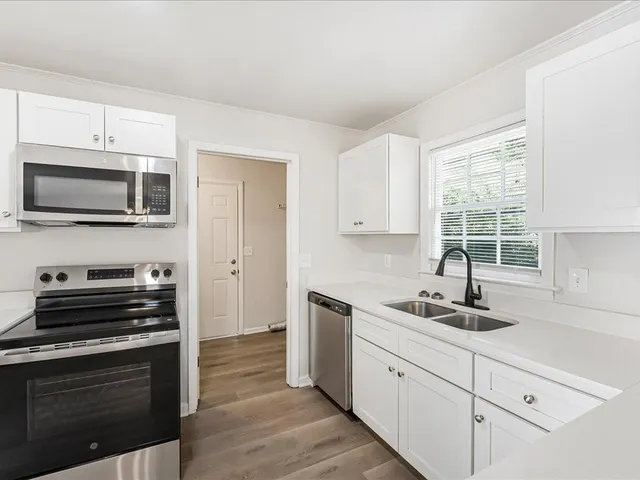 a kitchen with cabinets appliances a sink and a window