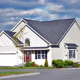 a view of a white house next to a yard and road