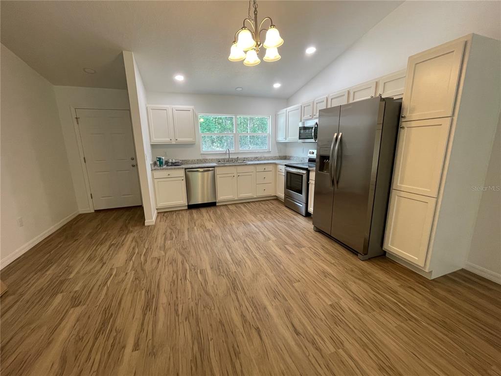 8829 East Marvin Street Floral City, FL 34436 - Photo 3 of 12 a kitchen with stainless steel appliances a refrigerator a sink dishwasher and a stove with wooden floors