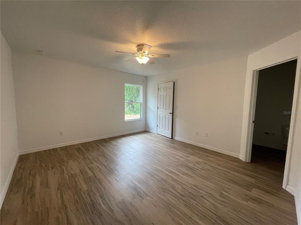 8829 East Marvin Street Floral City, FL 34436 - Photo 8 of 12 an empty room with wooden floor and windows