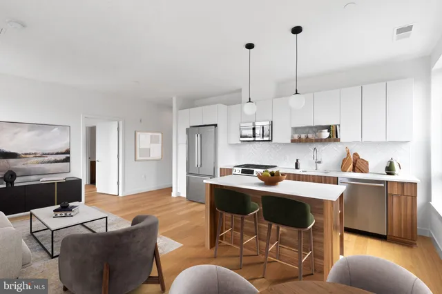 a kitchen with stainless steel appliances kitchen island granite countertop a stove a sink a dining table and chairs with white cabinets