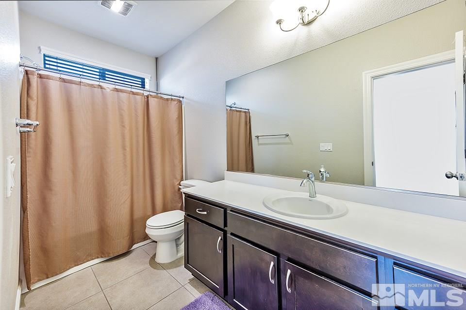 1920 Dark Horse Road, Unit A103 Reno, NV 89521 - Photo 15 of 15 a bathroom with a sink a toilet a mirror and shower curtain