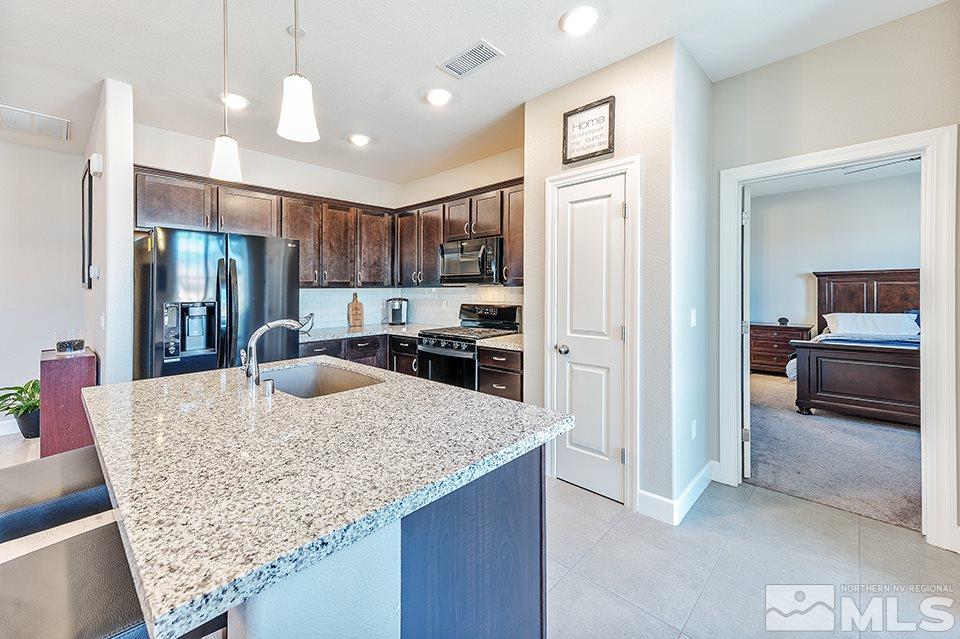 1920 Dark Horse Road, Unit A103 Reno, NV 89521 - Photo 7 of 15 a kitchen with kitchen island granite countertop a refrigerator and a sink