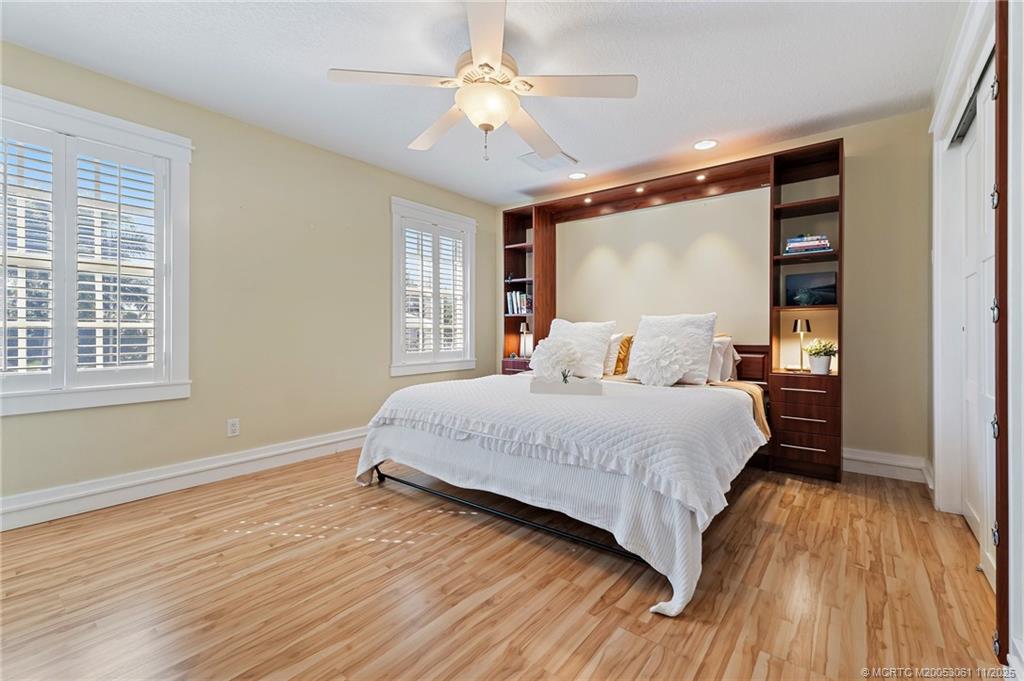 655 Southwest Salerno Road Stuart, FL 34997 - Photo 55 of 84 a bedroom with a large bed and a large window with wooden floor