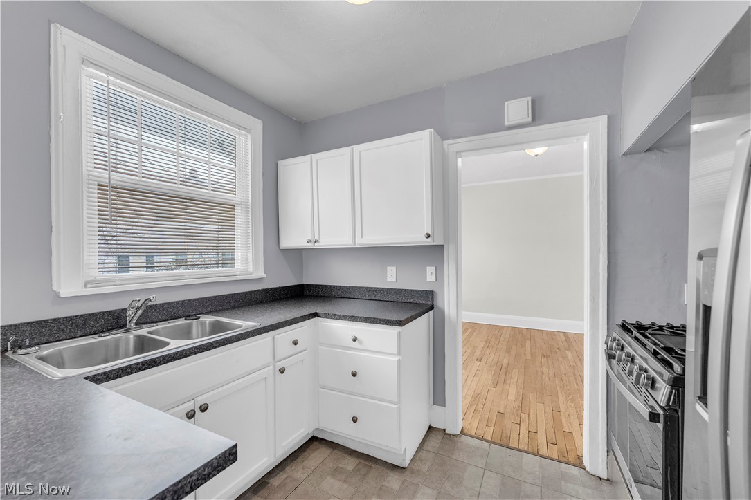 3318 Milverton Road, Unit 1/DN Shaker Heights, OH 44120 - Photo 9 of 21 Kitchen featuring white cabinetry, dark countertops, a double basin stainless steel sink, and a gas range