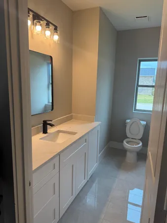 a spacious bathroom with a granite countertop sink toilet and mirror