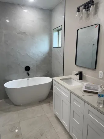 a bathroom with a granite countertop sink mirror and bathtub