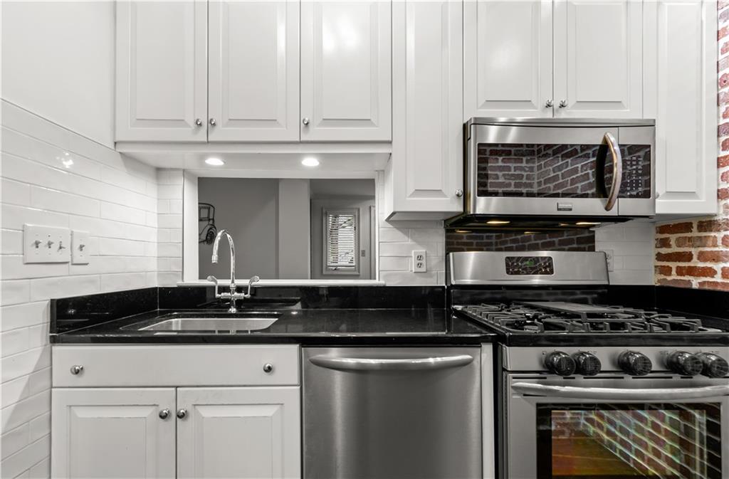 2840 Peachtree Road Northwest, Unit 312 Atlanta, GA 30305 - Photo 18 of 42 a kitchen with stainless steel appliances granite countertop a stove a sink and a white cabinets