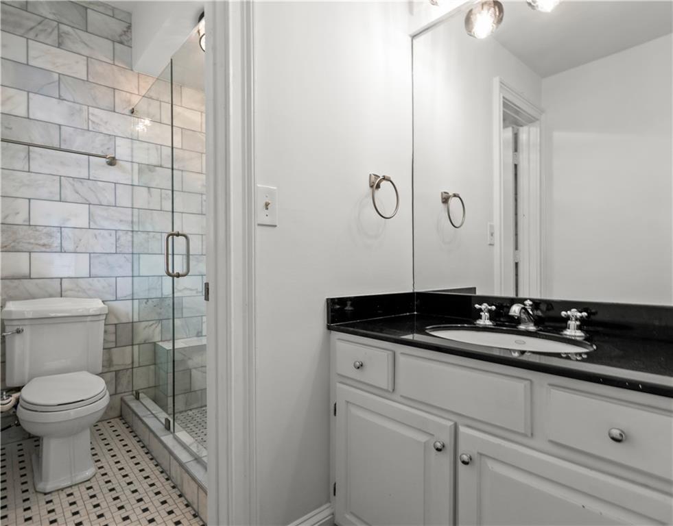 2840 Peachtree Road Northwest, Unit 312 Atlanta, GA 30305 - Photo 29 of 42 a bathroom with a granite countertop sink a toilet and a mirror