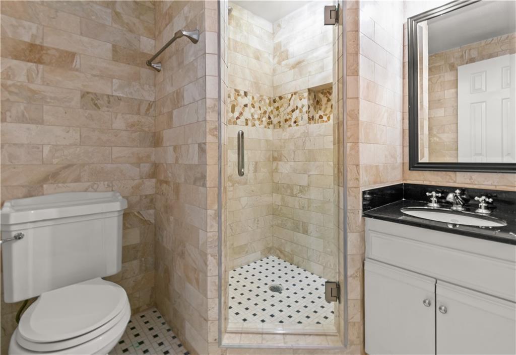 2840 Peachtree Road Northwest, Unit 312 Atlanta, GA 30305 - Photo 35 of 42 a bathroom with a sink a toilet a shower and a mirror