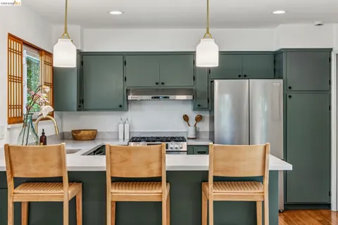 a kitchen with stainless steel appliances granite countertop a refrigerator a sink dishwasher a stove and a dining table with wooden floor