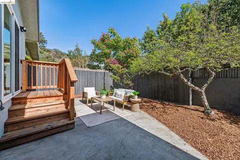 a view of a backyard with a large tree and wooden fence