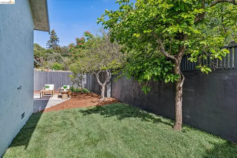 a backyard of a house with table and chairs under an umbrella