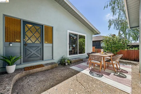 a view of a patio with table and chairs potted plants and floor to ceiling window
