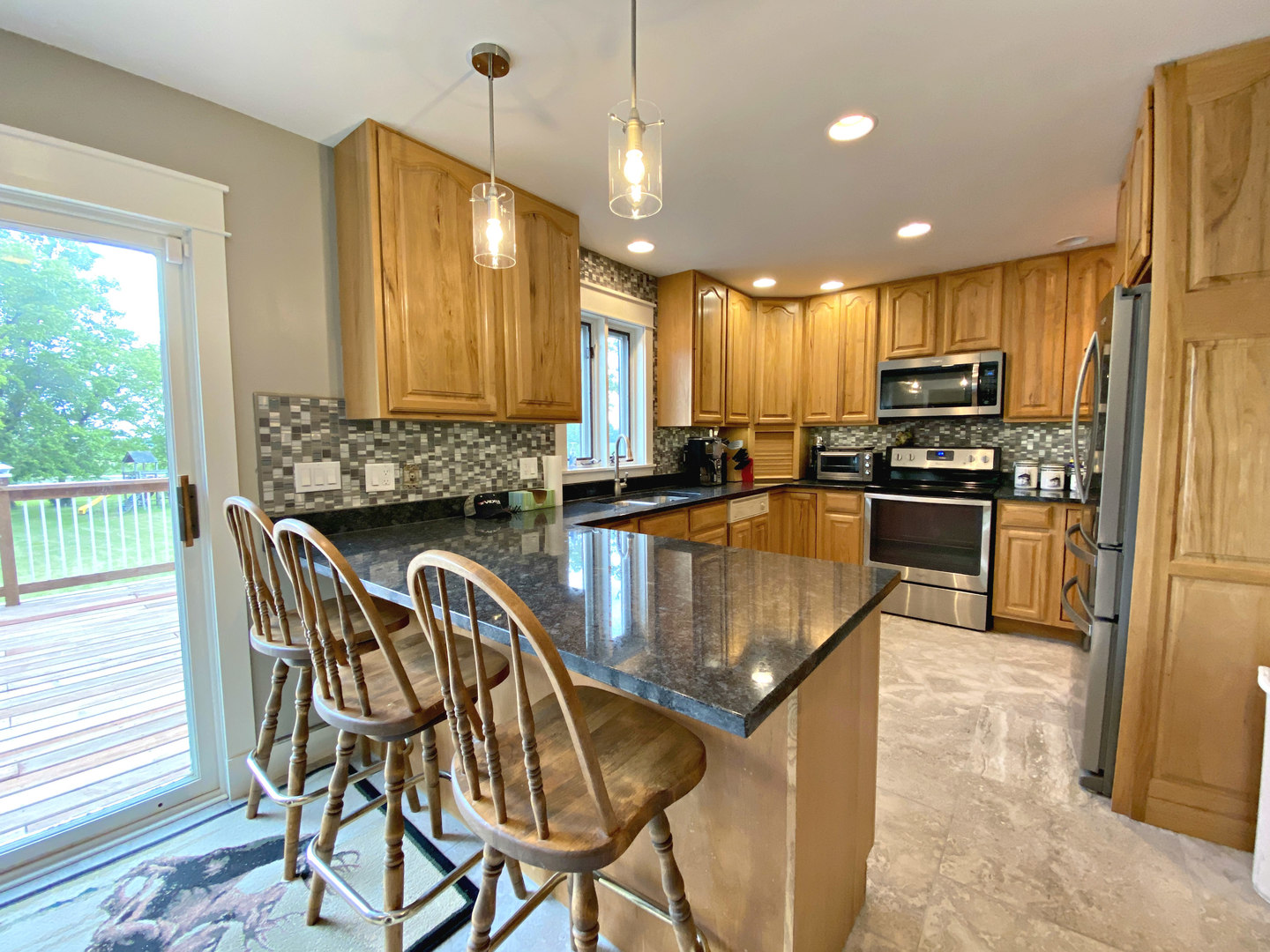 8101 Greenwood Road Hebron, IL 60034 - Photo 14 of 39 a kitchen with stainless steel appliances granite countertop a stove top oven a sink dishwasher a dining table and chairs with wooden floor