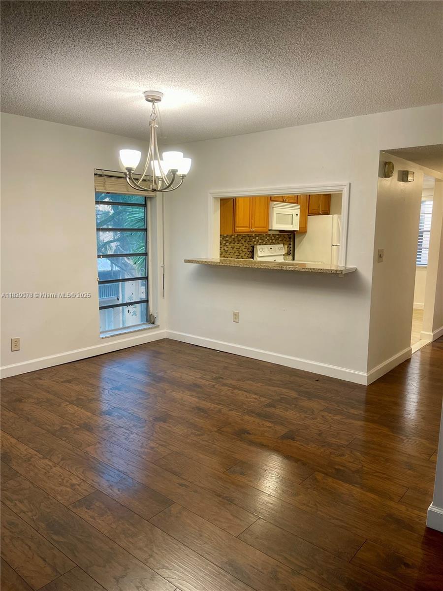 430 Commodore Drive, Unit 301 Plantation, FL 33325 - Photo 3 of 26 an empty room with wooden floor chandelier and windows
