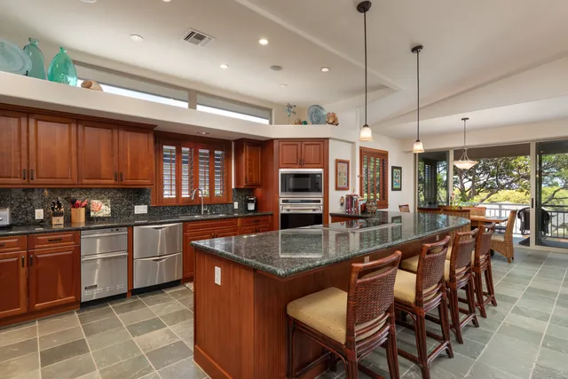 a kitchen with stainless steel appliances granite countertop a stove top oven a sink a dining table and chairs