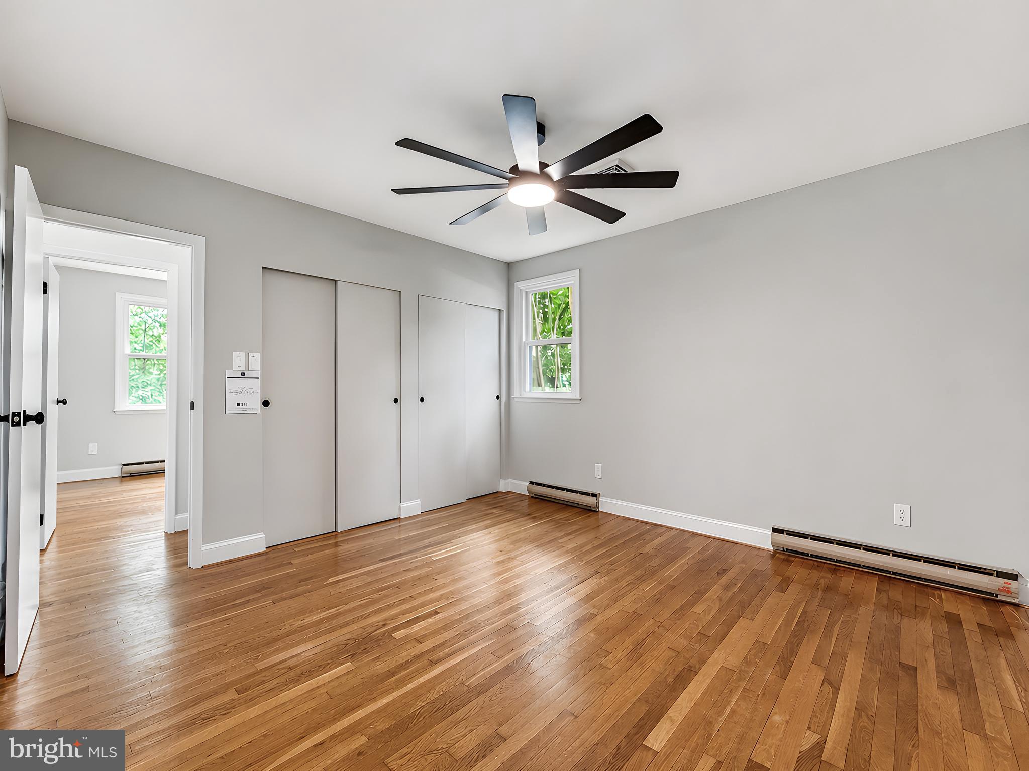 17248 Gum Landing Road St. Inigoes, MD 20684 - Photo 27 of 56 an empty room with wooden floor a ceiling fan and windows