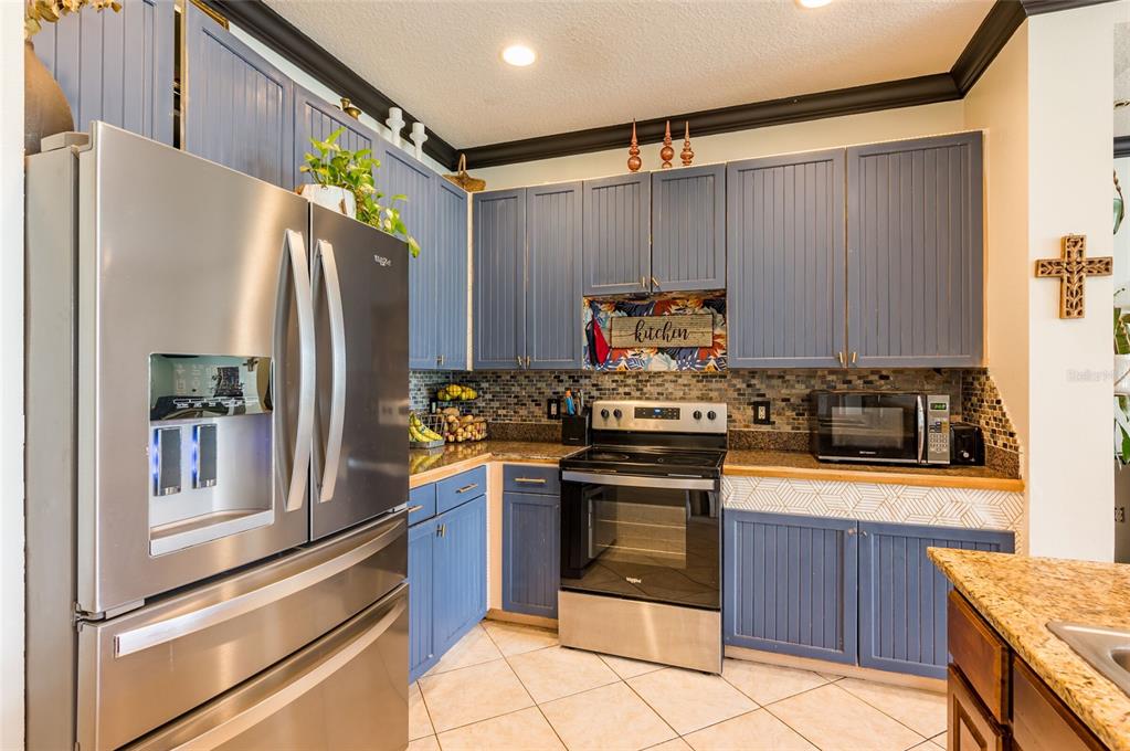 2204 1st Street, Unit F Indian Rocks Beach, FL 33785 - Photo 21 of 37 a kitchen with stainless steel appliances granite countertop a refrigerator and a stove top oven